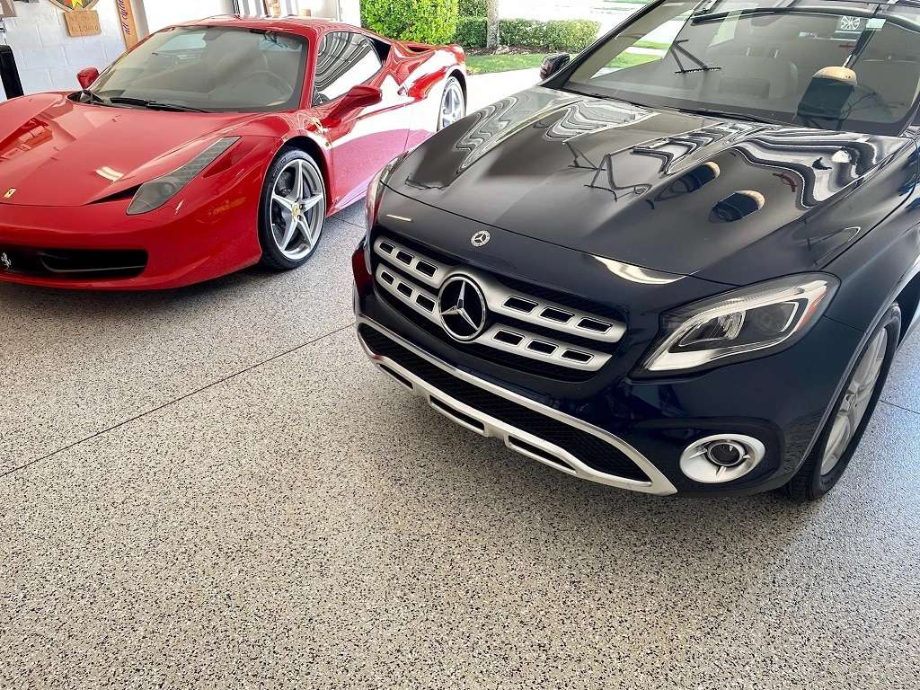 A red Ferrari and a black Mercedes-Benz parked side by side in a clean, indoor garage with a sleek epoxy floor coating. - Floor Coating Specialist - Bradenton, FL