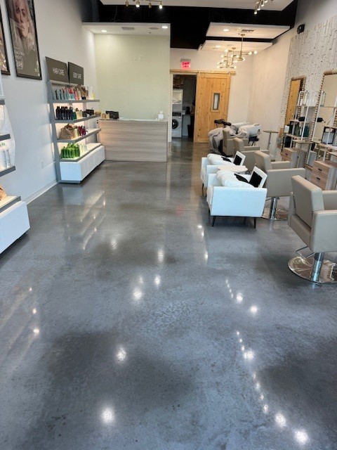 A modern hair salon with shiny epoxy floor coating, stylish chairs, sinks, product displays, and bright overhead lighting. - Floor Coating Specialist - Bradenton, FL