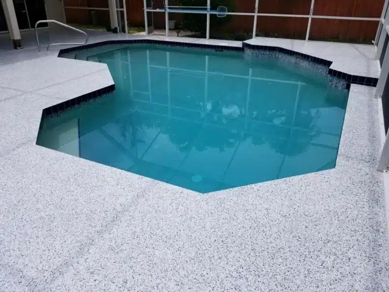 A small, light blue, geometric-shaped swimming pool with a speckled white concrete deck in a screened patio area, complemented by an adjacent epoxy floor coating for a sleek and durable finish. - Floor Coating Specialist - Bradenton, FL