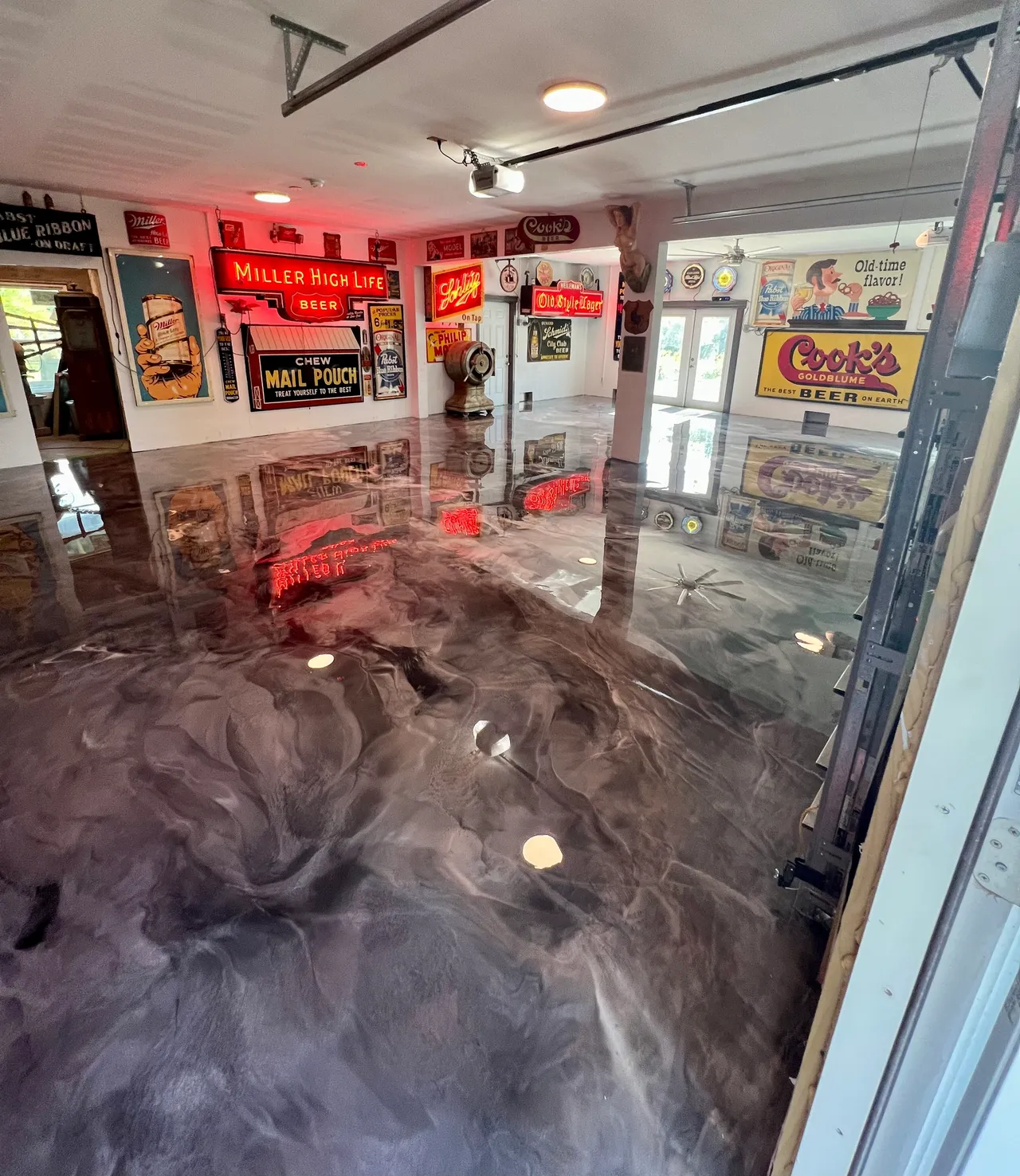 Garage with a shiny, marbled epoxy floor, decorated with retro beer and soda signs on the walls and bright overhead lighting. - Floor Coating Specialist - Bradenton, FL