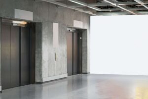 Two closed elevator doors set in a gray concrete wall, with bright lighting and shiny reflective floors in a modern building interior. - Floor Coating Specialist - Bradenton, FL